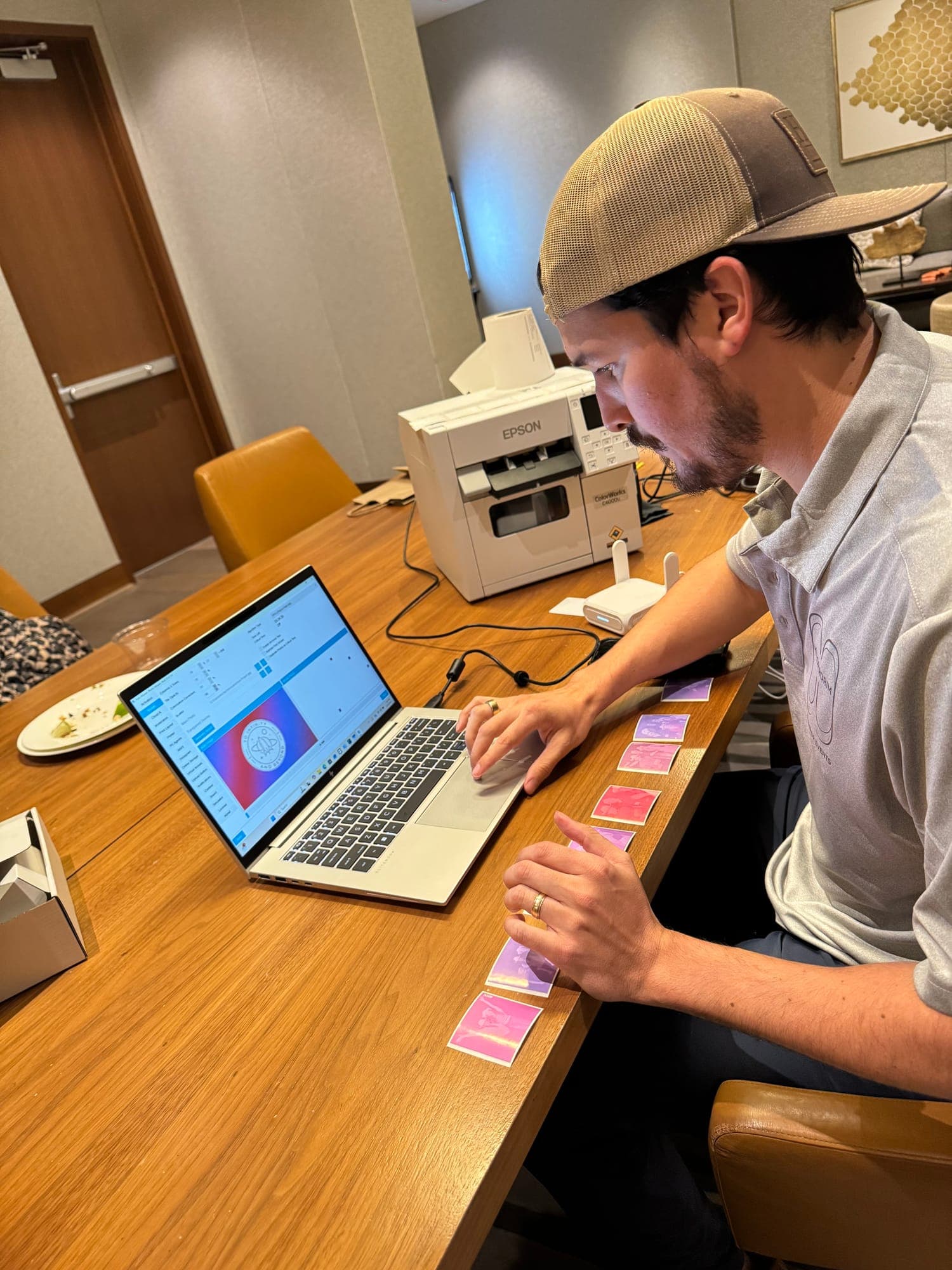 A founder at a laptop beside the printer, printing tiles for the mosaic