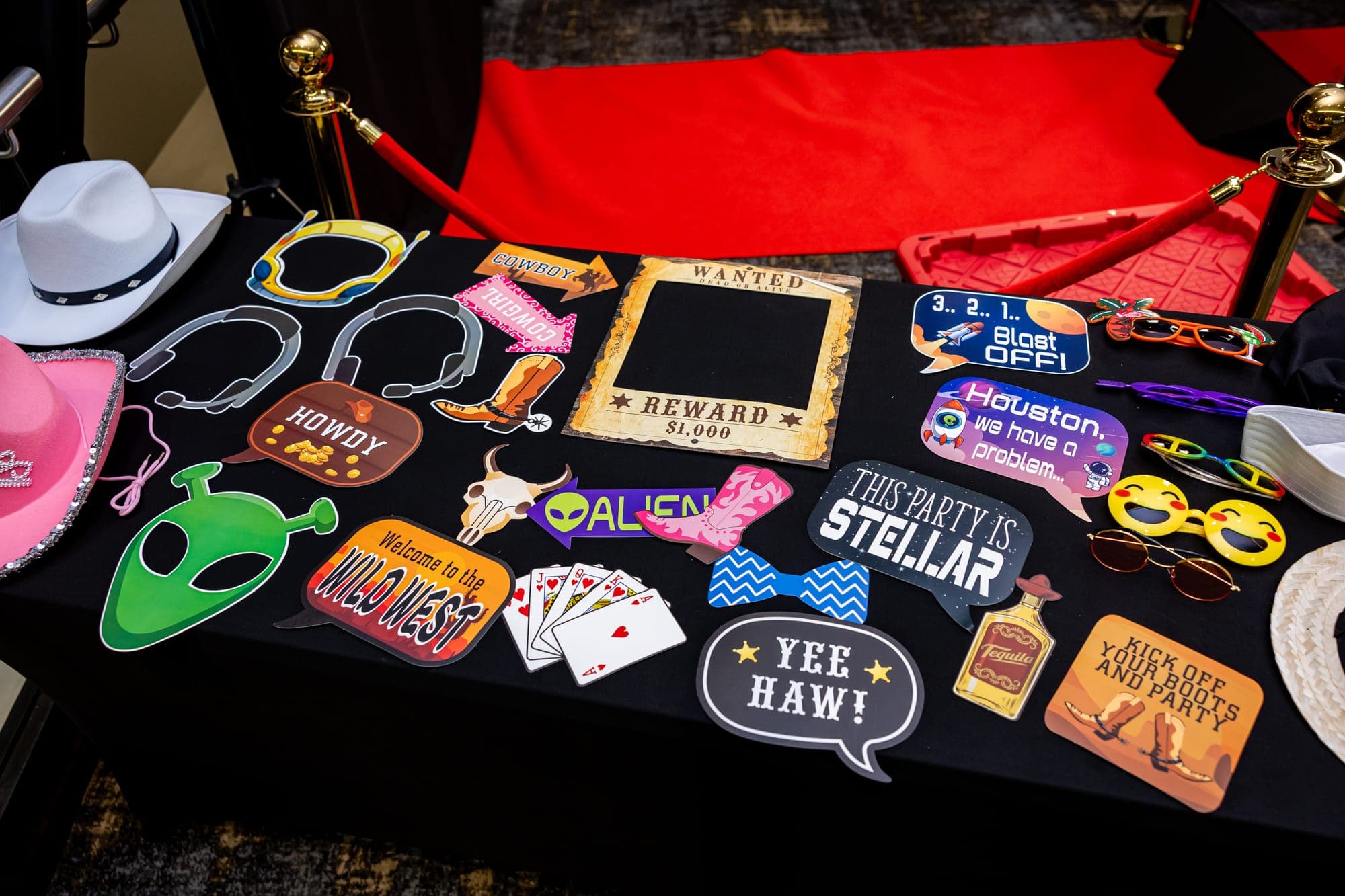 The prop table: cowboy hats, glasses, speech bubble signs and a Wanted poster frame beside the red carpet