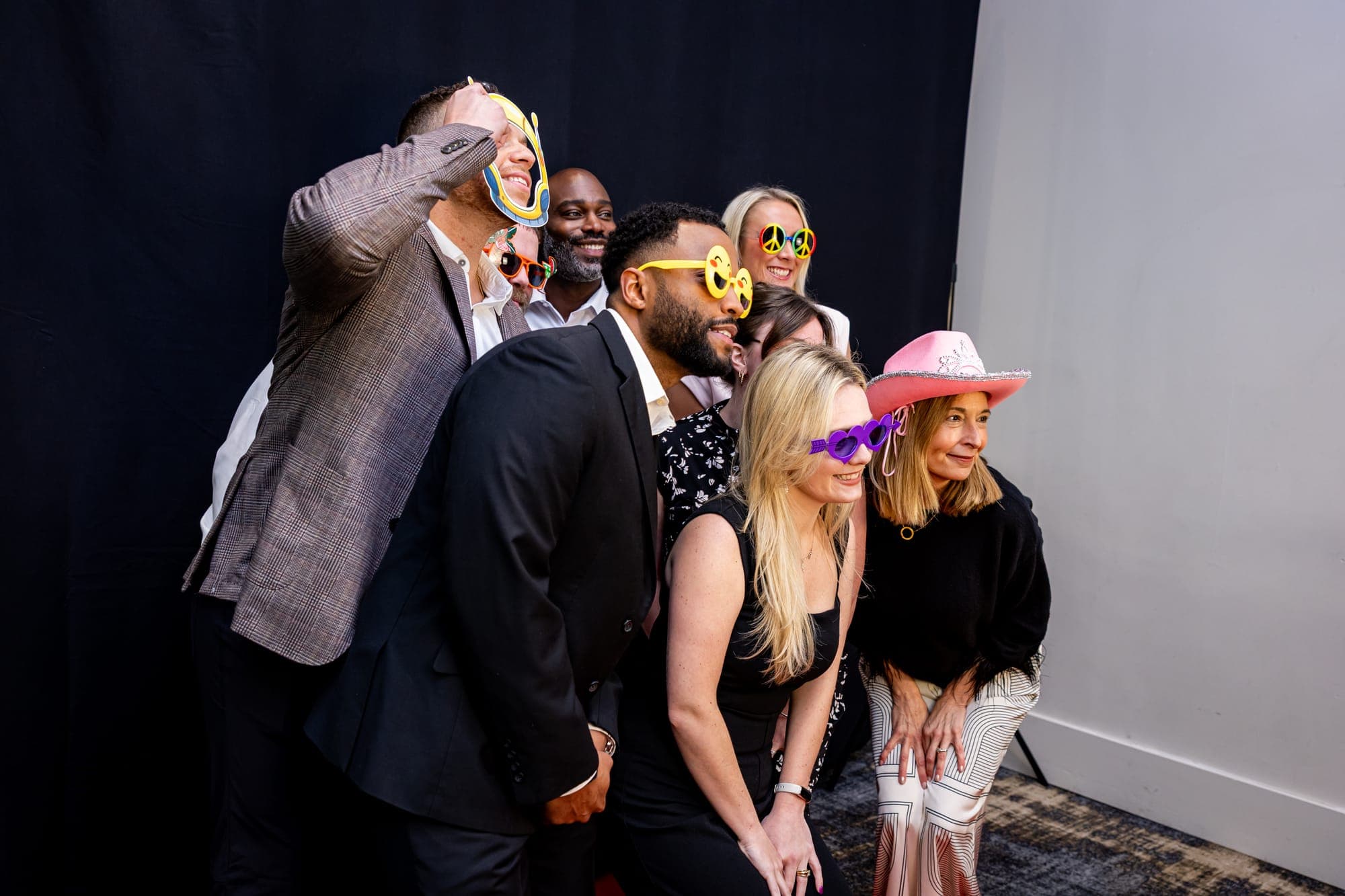 A group of guests in party props posing at the booth against a black backdrop