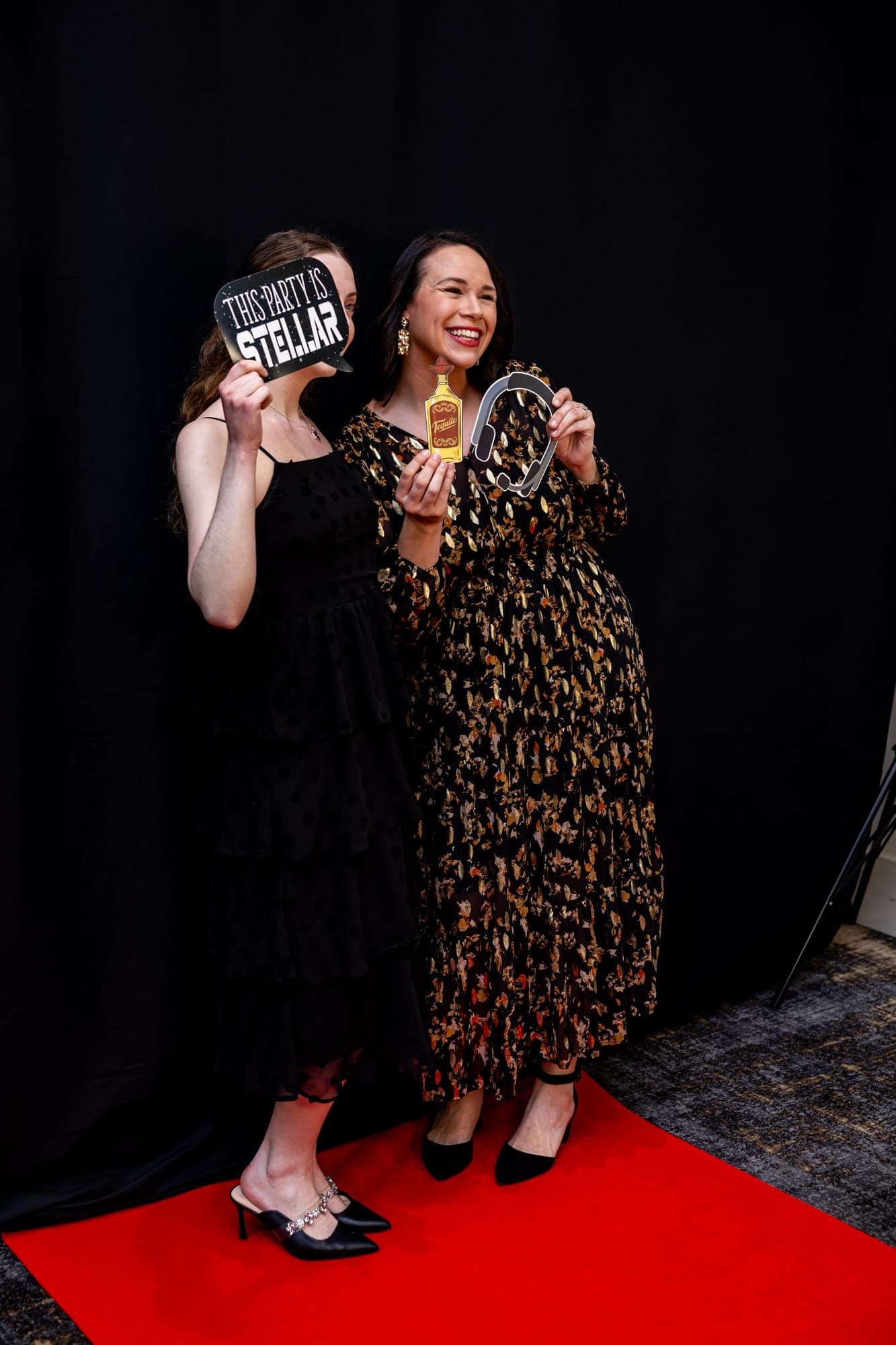 Two guests holding props on the red carpet at the booth